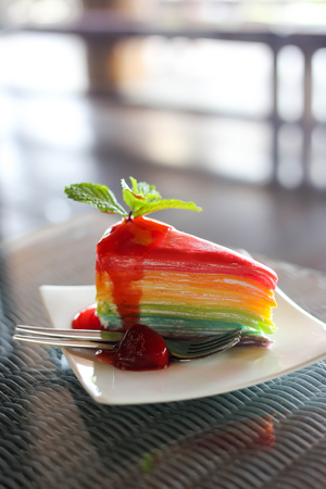 Rainbow Colorful crepe cake with strawberry sauce with cold coffee.の写真素材