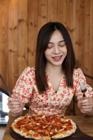 Beautiful Young asian woman eating delicious or yummy pizza.の写真素材