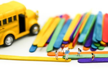 Miniature people : A group of young children getting on the schoolbus with Colorful ice cream sticks background.の写真素材