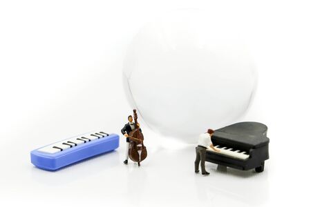 Miniature people : pianist playing piano and Violinist Man with mini world glass,playing musical instrument concept.の写真素材