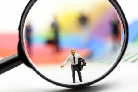 Miniature people : Successful businessman with magnifying glass of young businessman with Paper graph chartの写真素材