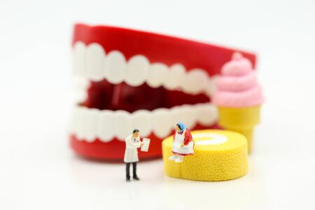 Miniature people : Dentist examining a patient's teeth with patient and sweet dessert, healthcare medical concept.の写真素材