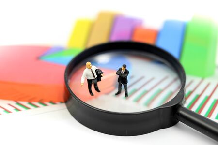Miniature people : Successful businessman with magnifying glass of young businessman with Paper graph chartの写真素材