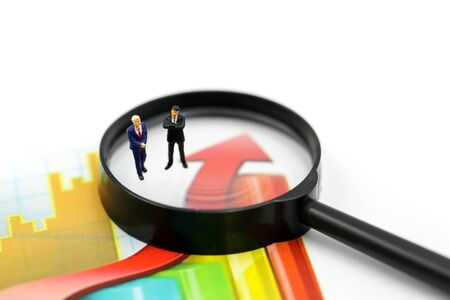 Miniature people : Successful businessman with magnifying glass of young businessman with Paper graph chart ,Business Growth concept.の写真素材
