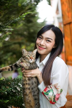 Beautiful asian woman carrying a cat on his hand with loveの写真素材