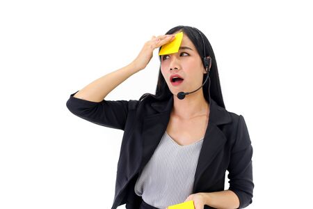 Beautiful asian woman Serious call center operator in wireless headset talking with customerの写真素材