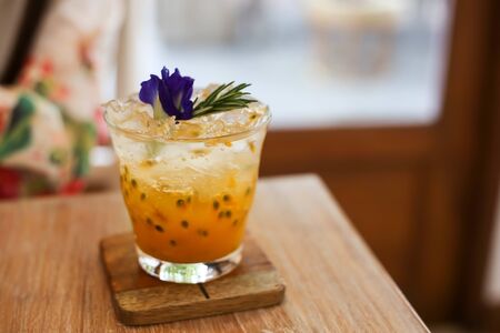 Passion fruit juice iced in a glass on wooden table in cafe.