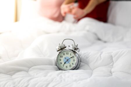 Clock alarm on bed in bedroom  in the morning.の写真素材