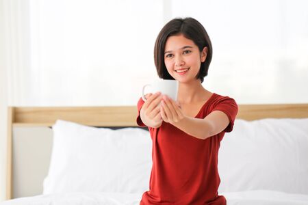 Happy Couple  asia woman enjoy together with drink morning coffee, fresh tea or hot milk in cup on the bed in morning.の写真素材