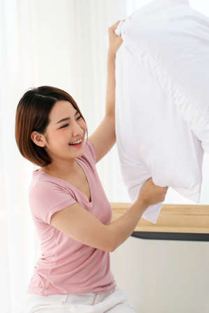 Happy young couple friend beautiful asia women having a pillow fight in their bedroom.の写真素材