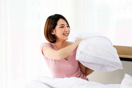 Happy young couple friend beautiful asia women having a pillow fight in their bedroom.の写真素材