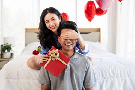 Beautiful young couple surprise with rose and gift in bedroom,Valentine's Day  concept.の写真素材