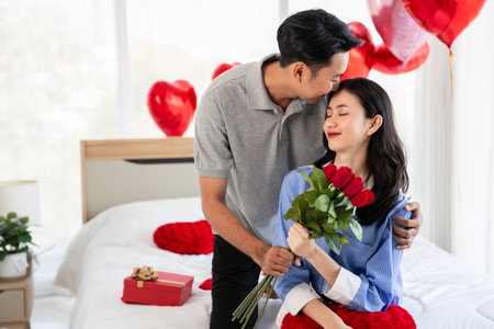 Man giving a rose and a kiss to his beautiful wife in bed Valentine's Day  concept.の写真素材