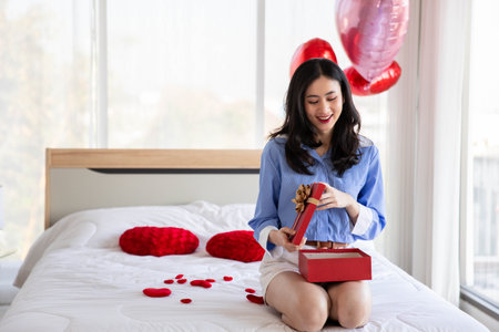 Smiling happy woman in love with gift box and rose in bedroom,Valentine's Day  concept.の写真素材