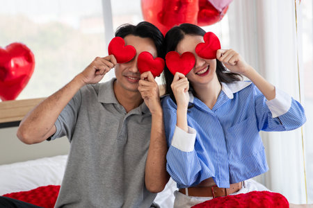 Couple in love holding red heart-shaped cards and smiling happy in Valentine's Day concept.の写真素材