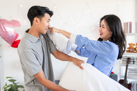 Happy young couple having fun pillow fight in bedroom Valentine day,の写真素材