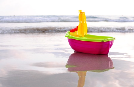 Plastic toy boat on a beach sandの写真素材