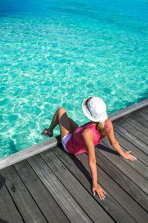 woman in hat sitting on the bridge in maldivesの写真素材