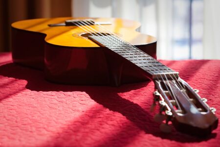 acoustic guitar lying on bed