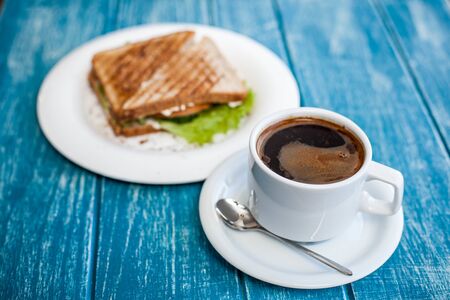 Breakfast with a cup of coffee and two toasted sandwiches	の写真素材