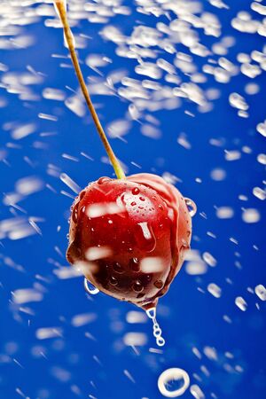ripe cherry in water spray in the blue backgroundの写真素材
