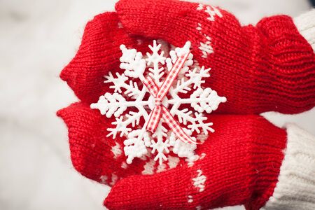 Hands in the mittens holding decorative snowflake	の写真素材