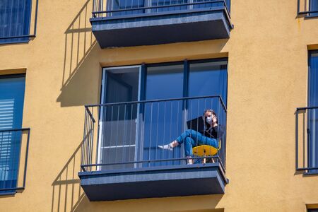 Woman in protection mask working on laptop at balcony. Work from homeの写真素材