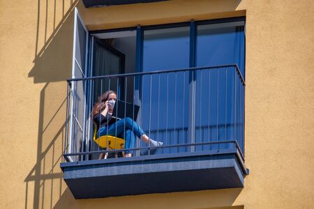 Woman in protection mask working on laptop at balcony. Work from homeの写真素材