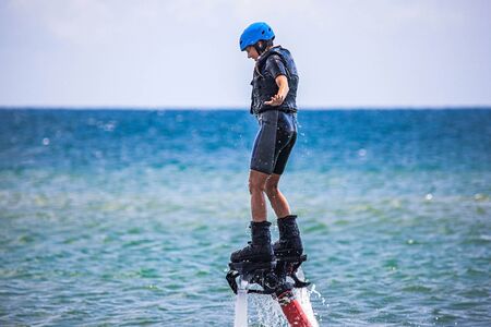 Young woman is flying at the aquatic flyboard. Water extreme sportの写真素材