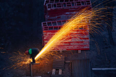 Industrial worker sawing metal with many sharp sparksの写真素材