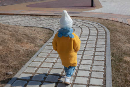 Beautiful baby in an orange coat and white hat and scarfの写真素材