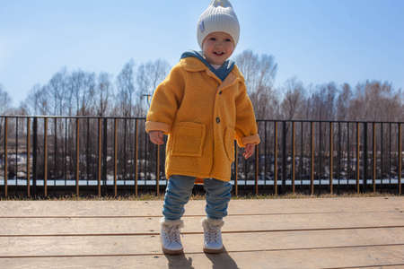 Beautiful baby in an orange coat and white hat and scarf