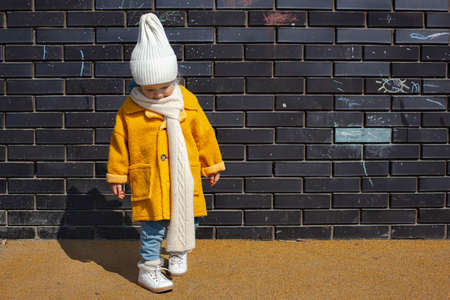 Beautiful baby in an orange coat and white hat and scarf