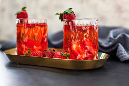 Red drink with ice and strawberry with leaves