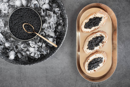 Black caviar in can on ice and bread with butter on golden plate. High quality photoの写真素材