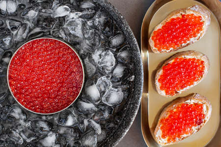 Red caviar in can on ice and bread with butter on golden plate. High quality photoの写真素材