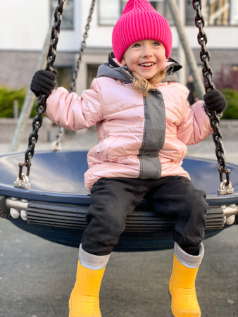 Cute little girl having fun on a swing on beautiful autumn dayの写真素材