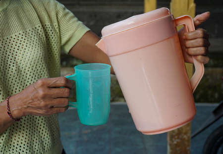 People pour water into glasses. Water is poured from a pink teapot.の写真素材