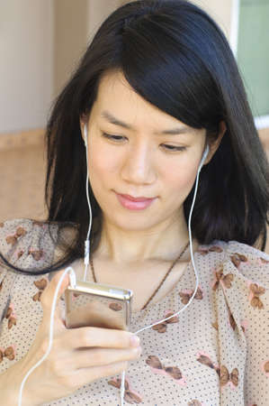Pretty Asian woman listening the music with earbuds