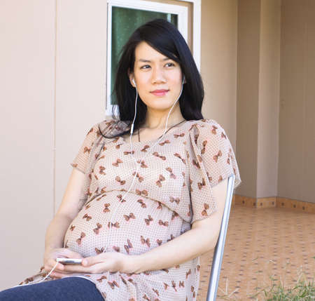 Pregnant Asian woman listening the music with earbudsの写真素材
