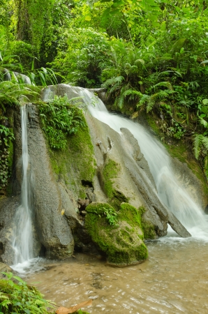 Beautiful waterfall surrounded by forests and mountainsの写真素材