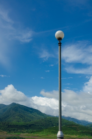 Blue sky and mountain background with luminaire pole on a good weatherの写真素材