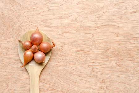 shallot on wooden spoon and wood texture backgroundの写真素材