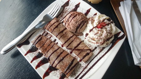 chocolate crepe served with ice cream and whipping cream, topped with chocolate