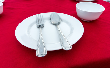 empty dish with fork and spoon on red table cloth
