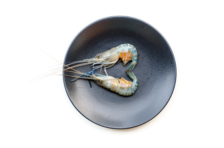 Close up fresh shrimp with eggs on black dish isolated on white backgroundの写真素材