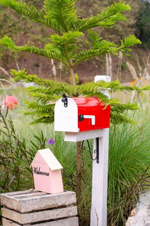Red and white metal mailbox in the outdoor gardenの写真素材