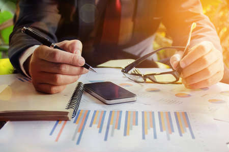 business documents on office table with smartphone and graph financial diagram and Business people working at officeの写真素材