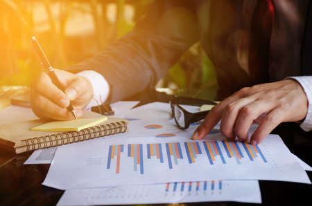 Businesswomen analyzing investment charts on the desk. Pen in hand