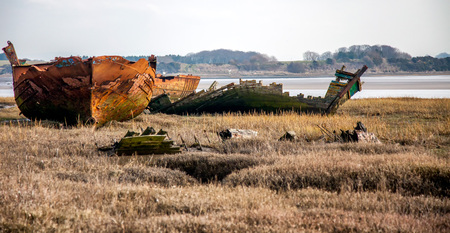 boat wrecks lie rotting away on the marshes of the river Wyre estuaryの写真素材